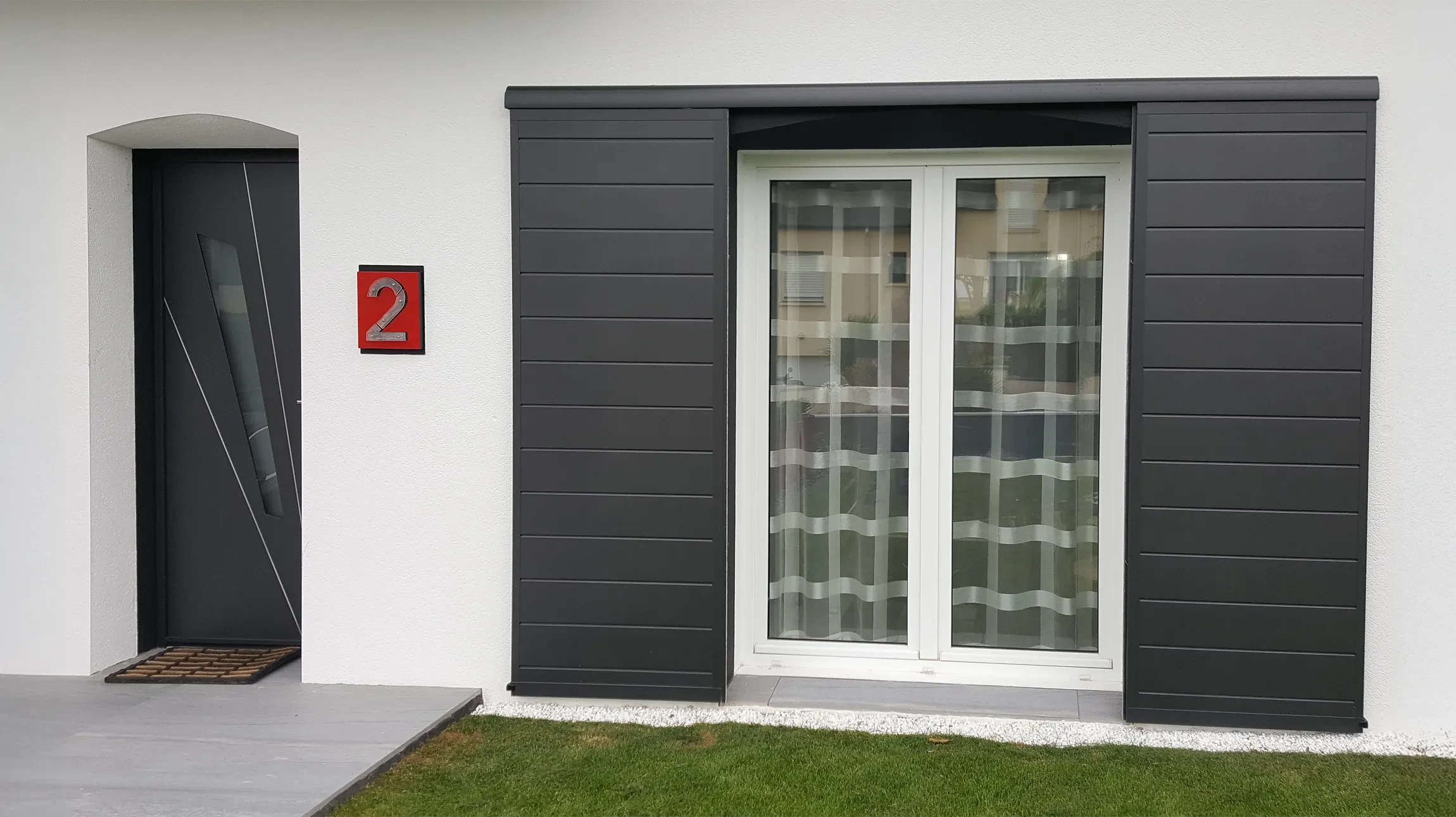 Façade moderne de maison individuelle avec entrée principale et extension vitrée