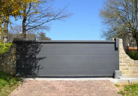 Portail coulissant moderne en aluminium gris anthracite installé devant une propriété résidentielle