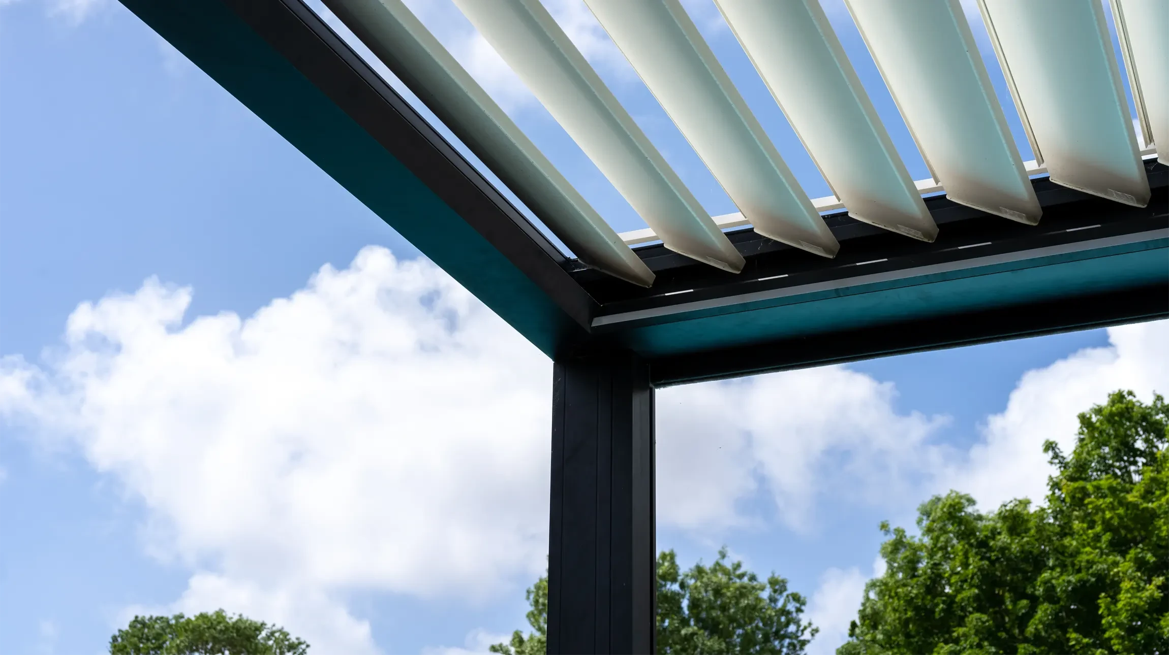 Terrasse couverte moderne avec pergola en bois, mobilier d'extérieur contemporain noir comprenant canapé modulaire, fauteuils en résine tressée et table basse design