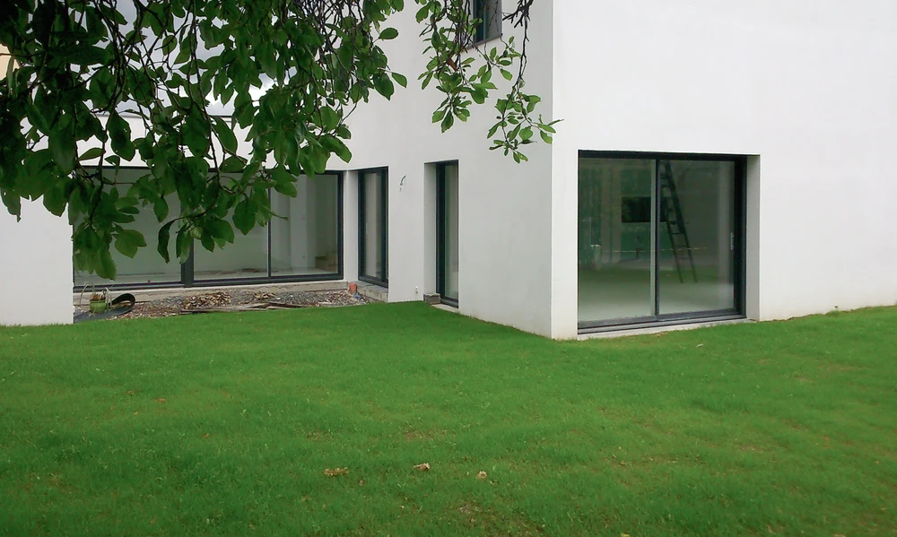 Terrasse extérieure moderne avec mobilier de jardin blanc et rangements anthracite sur plancher bois