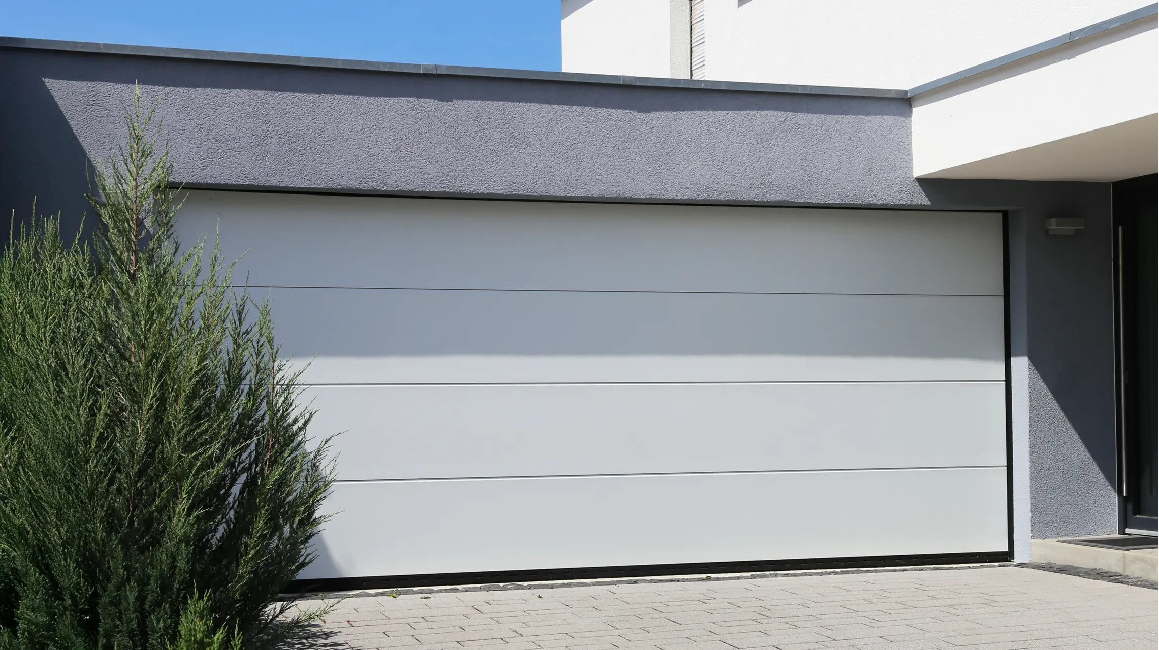 Façade résidentielle contemporaine avec porte de garage sectionnelle blanche à panneaux rectangulaires
