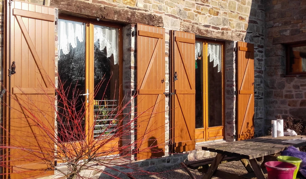 Extérieur résidentiel avec portillon en aluminium anthracite installé entre piliers en pierre naturelle multicolore
