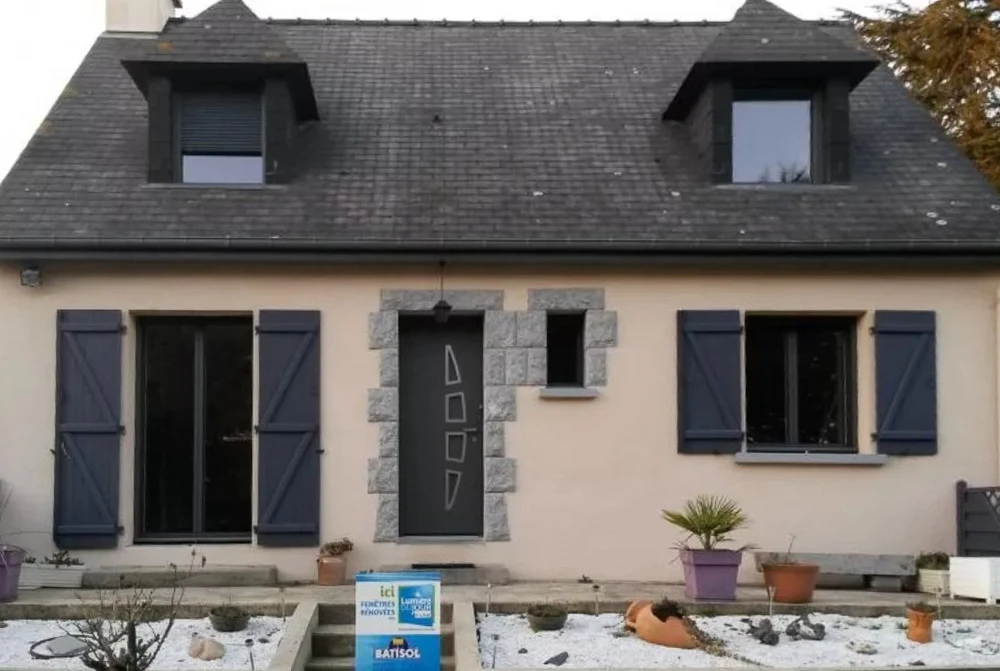 Extérieur d'un bâtiment en pierre avec grande porte d'entrée métallique moderne à trois vantaux