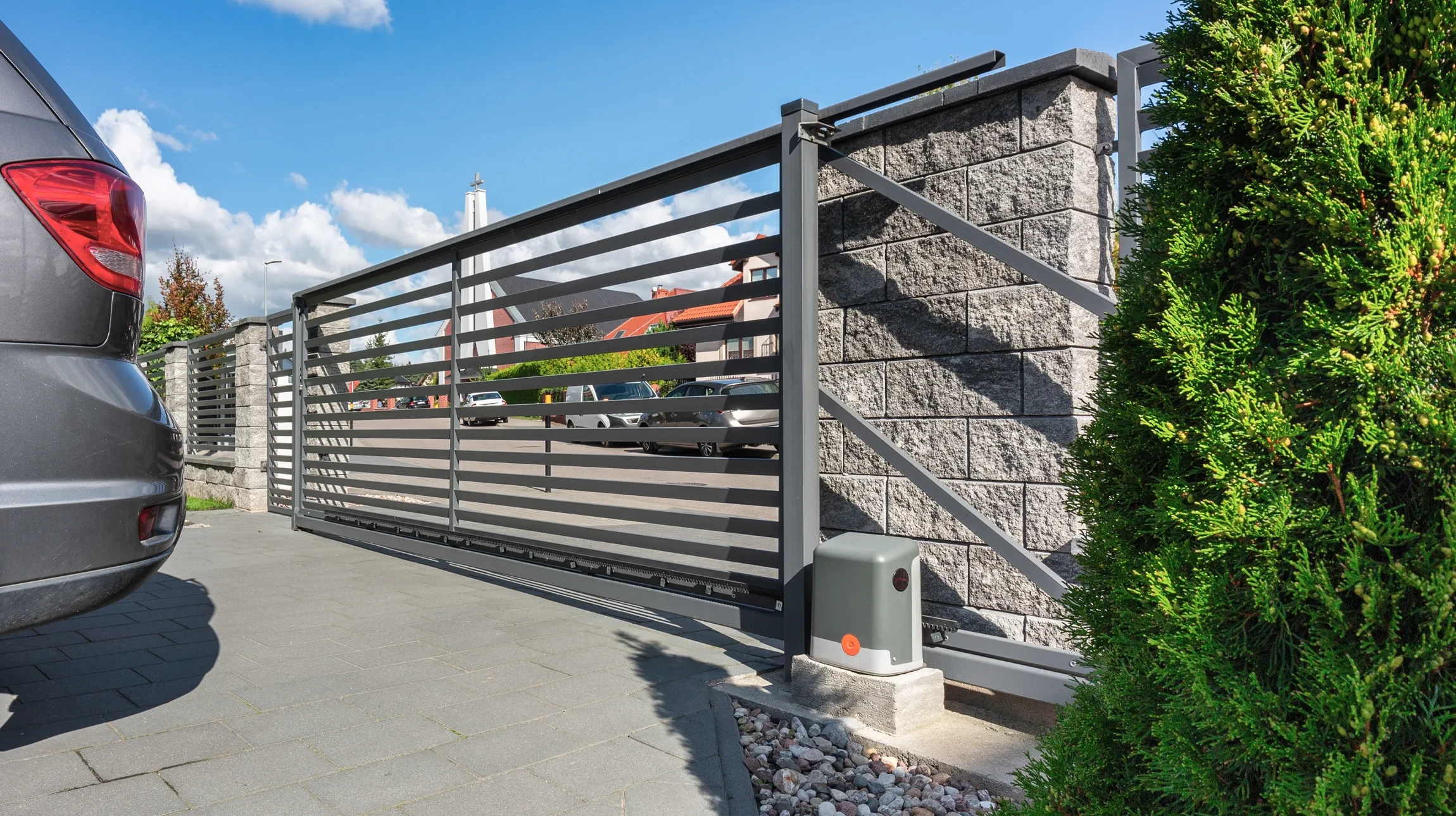 Un technicien en salopette rouge travaille sur une porte vitrée d'un bâtiment commercial moderne
