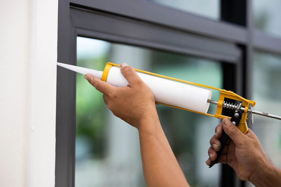 Scène extérieure d'atelier de menuiserie avec artisan utilisant une ponceuse orbitale électrique noire sur planche de bois naturel