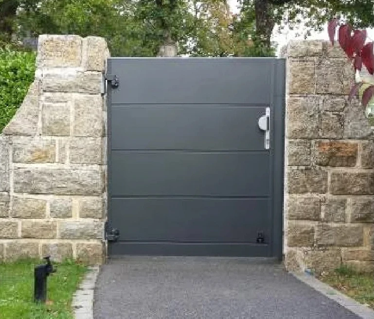 Extérieur d'un bâtiment en pierre avec grande porte d'entrée métallique moderne à trois vantaux