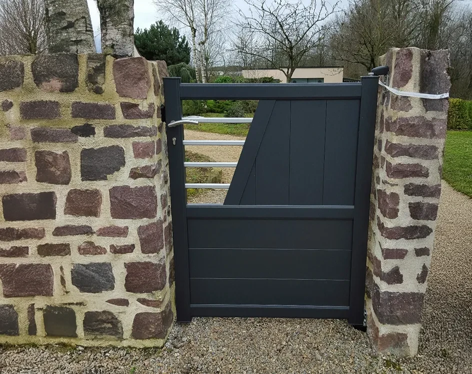Extérieur d'un bâtiment en pierre avec grande porte d'entrée métallique moderne à trois vantaux